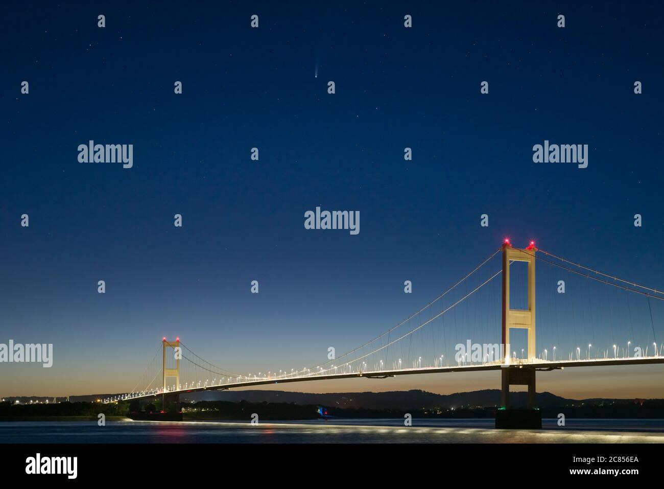 Comet C/2020 F3 Neowise over the Severn Bridge between England and Wales at twilight in July 2020 viewed from the bank of the River Severn at Aust, Gloucestershire, England. Stock Photo