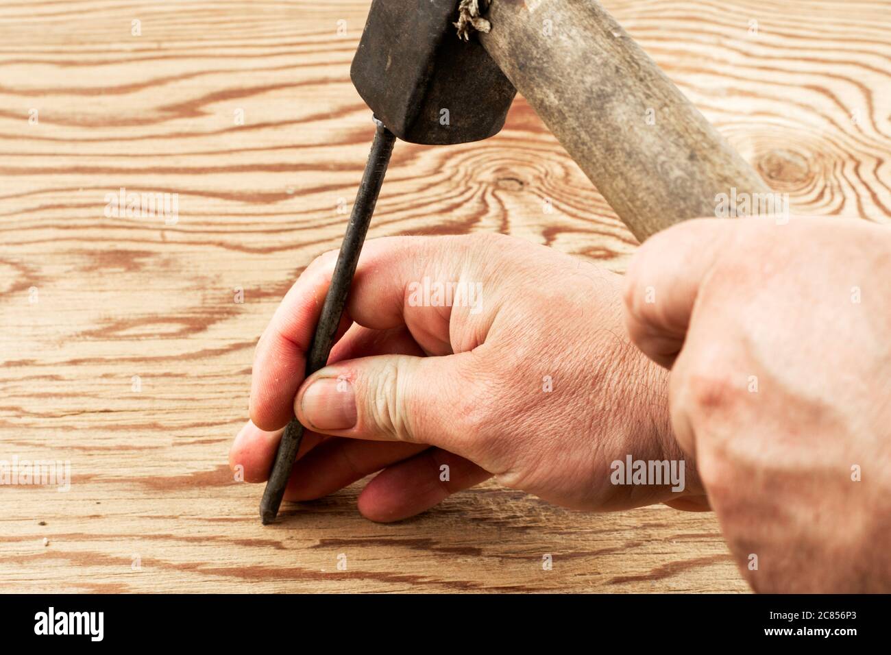 the man hammers a nail into a damaged surface Stock Photo Alamy