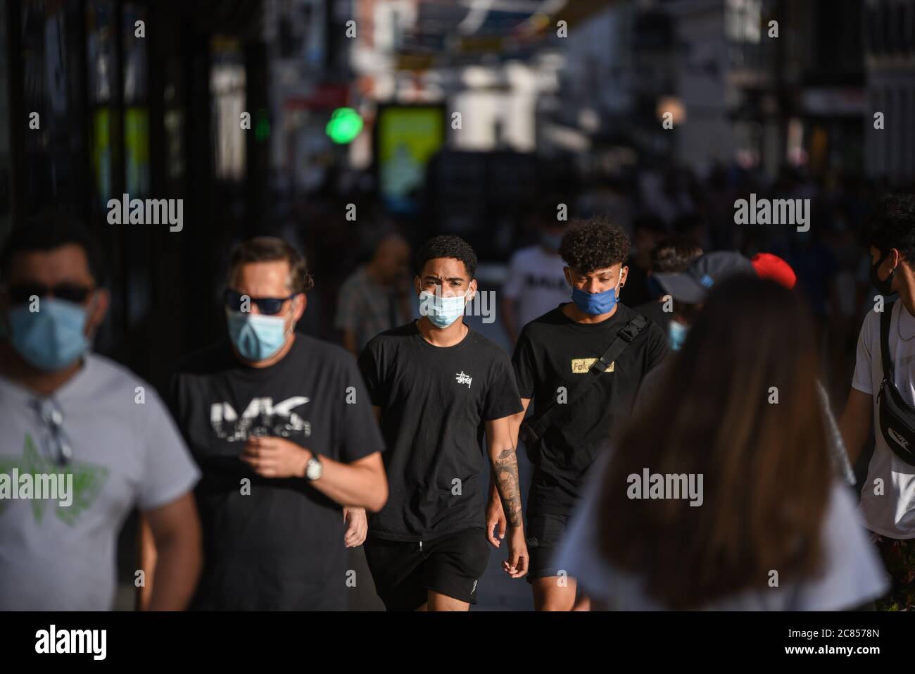People walk along the streets while wearing face masks as a preventive measure against the