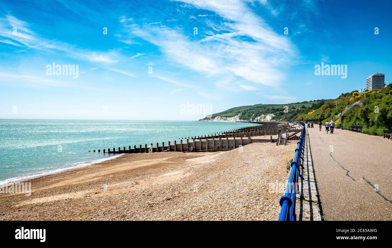 Eastbourne promenade and the South Downs, England. A bright, summer view west along the sea front towards the white cliffs of the Sussex coastline. Stock Photo