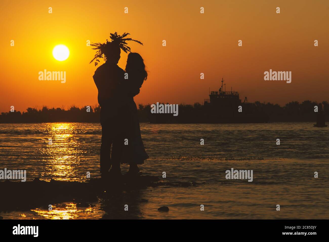 Young couple in love meet sunrise (sunset) on the banks of the sea. Stock Photo