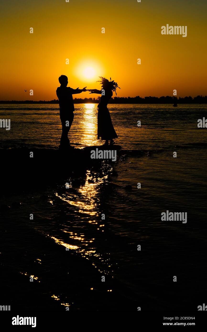 Young couple in love meet sunrise (sunset) on the banks of the river. Stock Photo