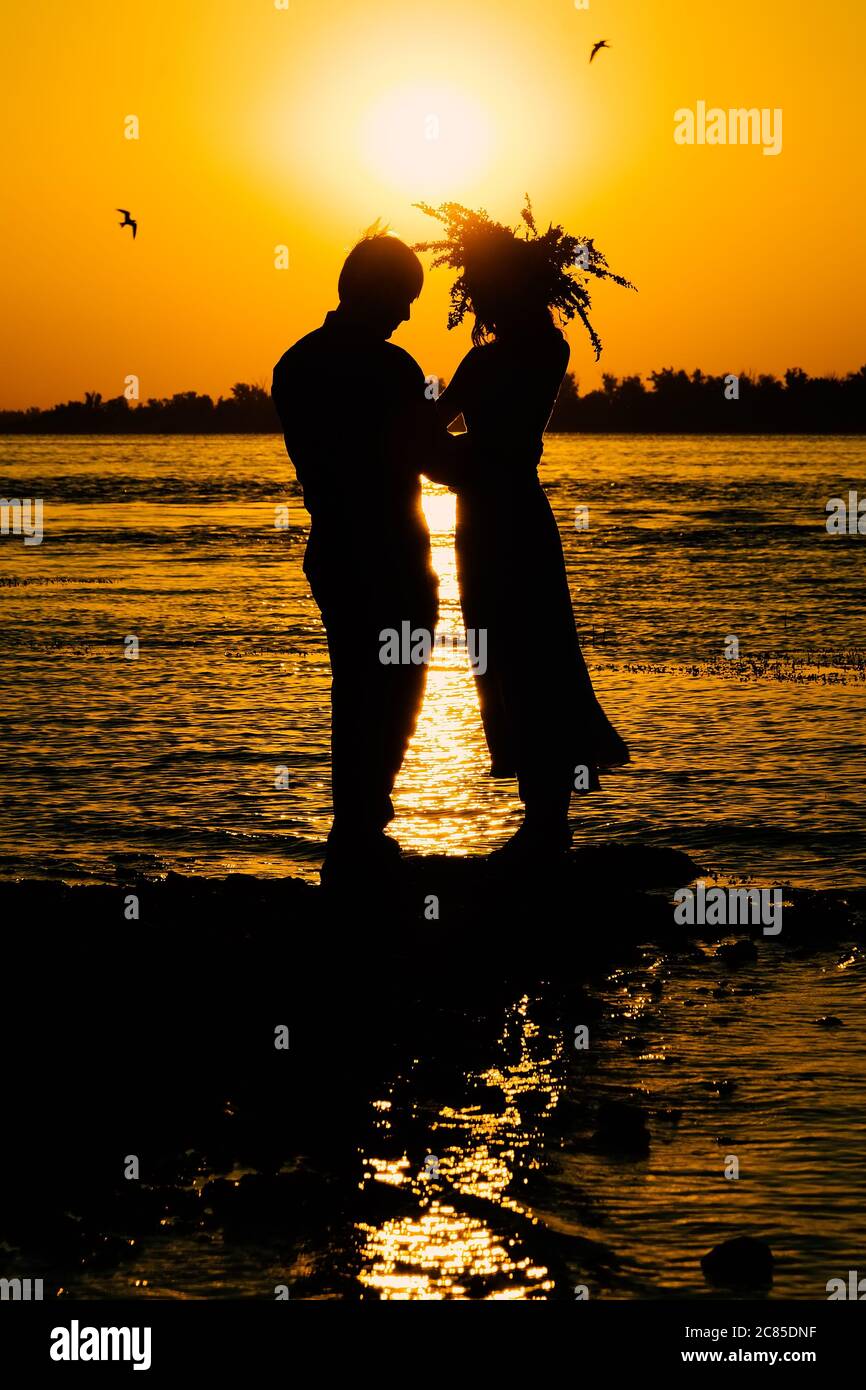 Young couple in love meet sunrise (sunset) on the banks of the river. Stock Photo