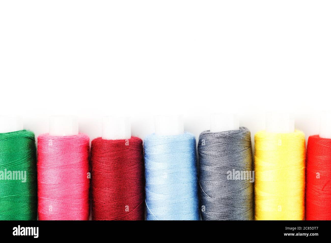 Sewing threads of different colors on reels on a white background. Free ...
