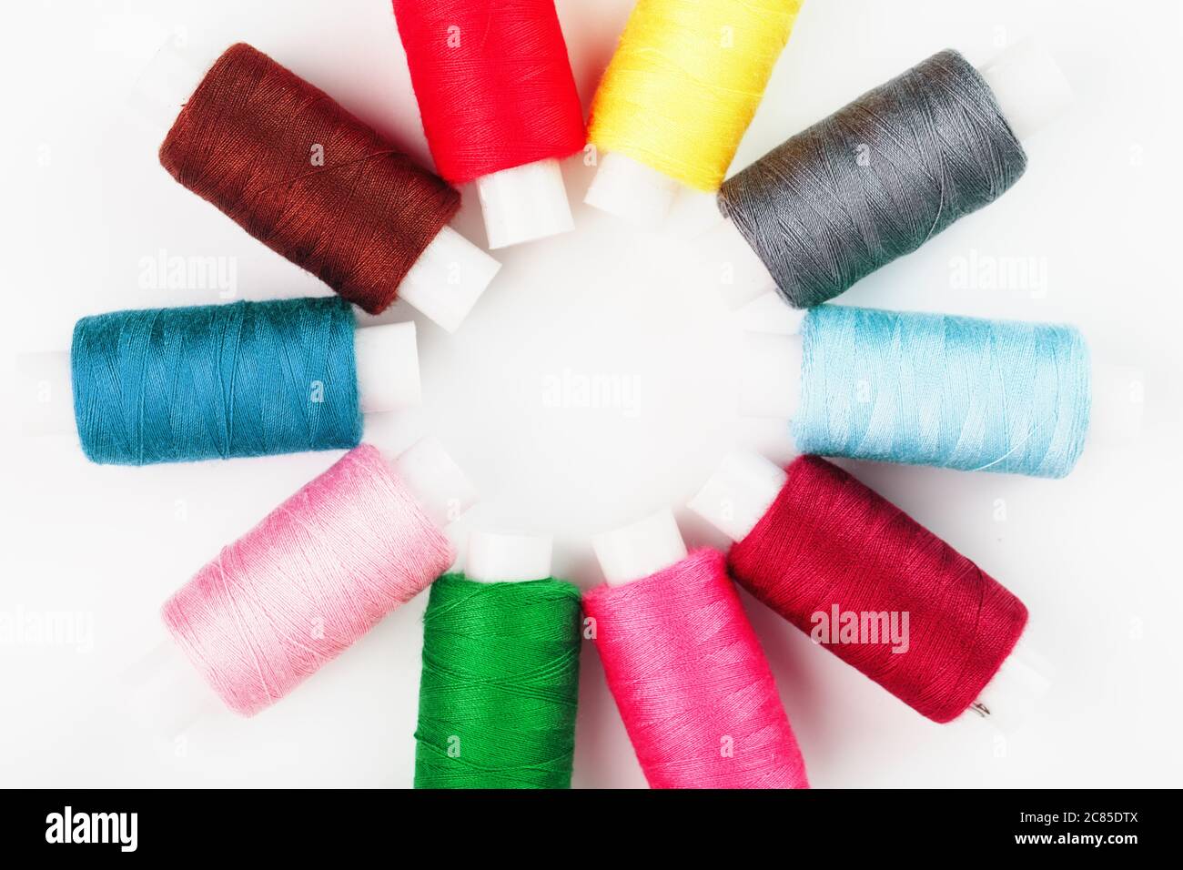 Sewing threads of different colors on reels on a white background in a ...
