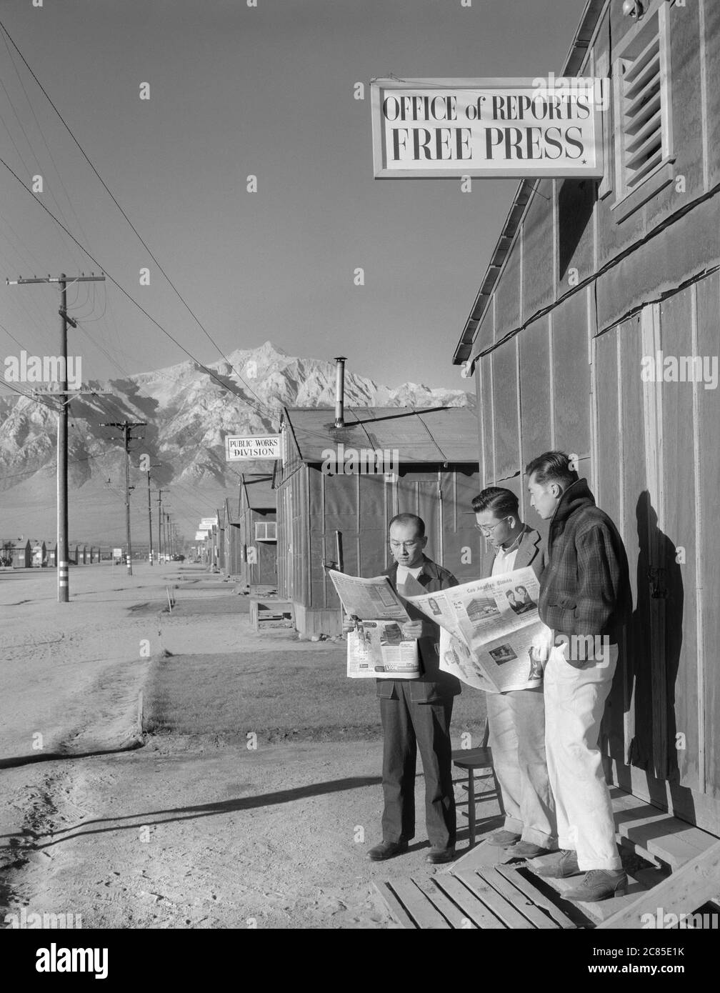 Roy Takeno (Editor) and group reading Newspapers in front of Office, Yuichi Hirata, Nabuo Samamura, Manzanar Relocation Center, California, USA, Ansel Adams, Manzanar War Relocation Center photographs, 1943 Stock Photo