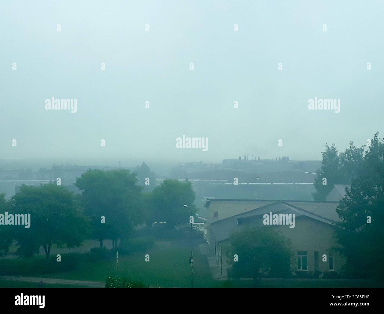 Fog over the industrial zone. Summer industrial landscape with fog in the sky. Cloudy. Noon. Horizontal photo. Summer landscape Stock Photo