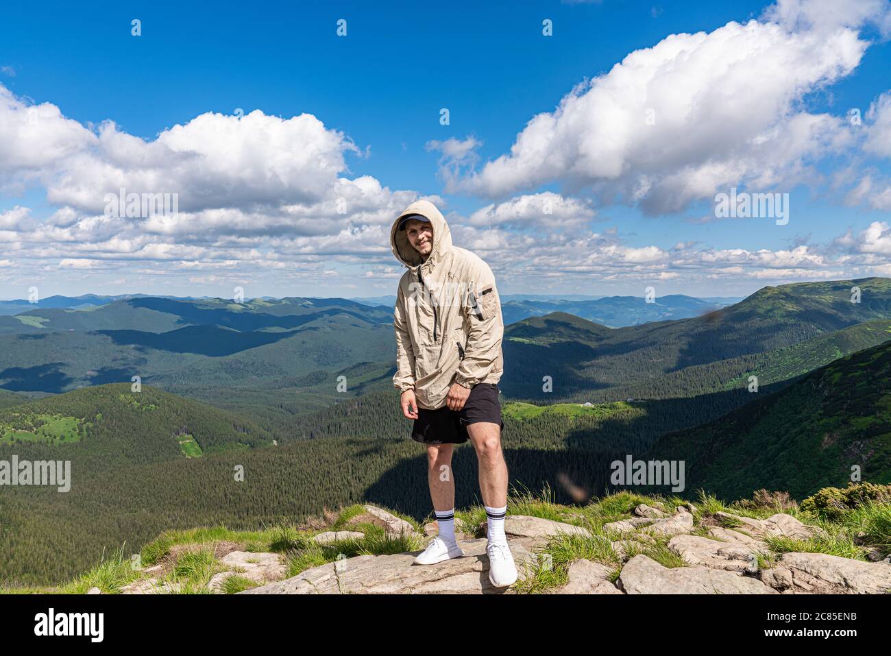 Tourist Man Standing On Mountain Top, Happy Smiling Over Beautiful Landscape Stock Photo