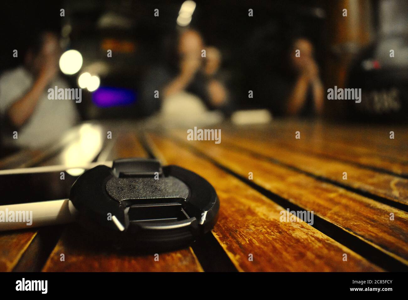 Black cover for a camera lens on a wooden table in a pub Stock Photo