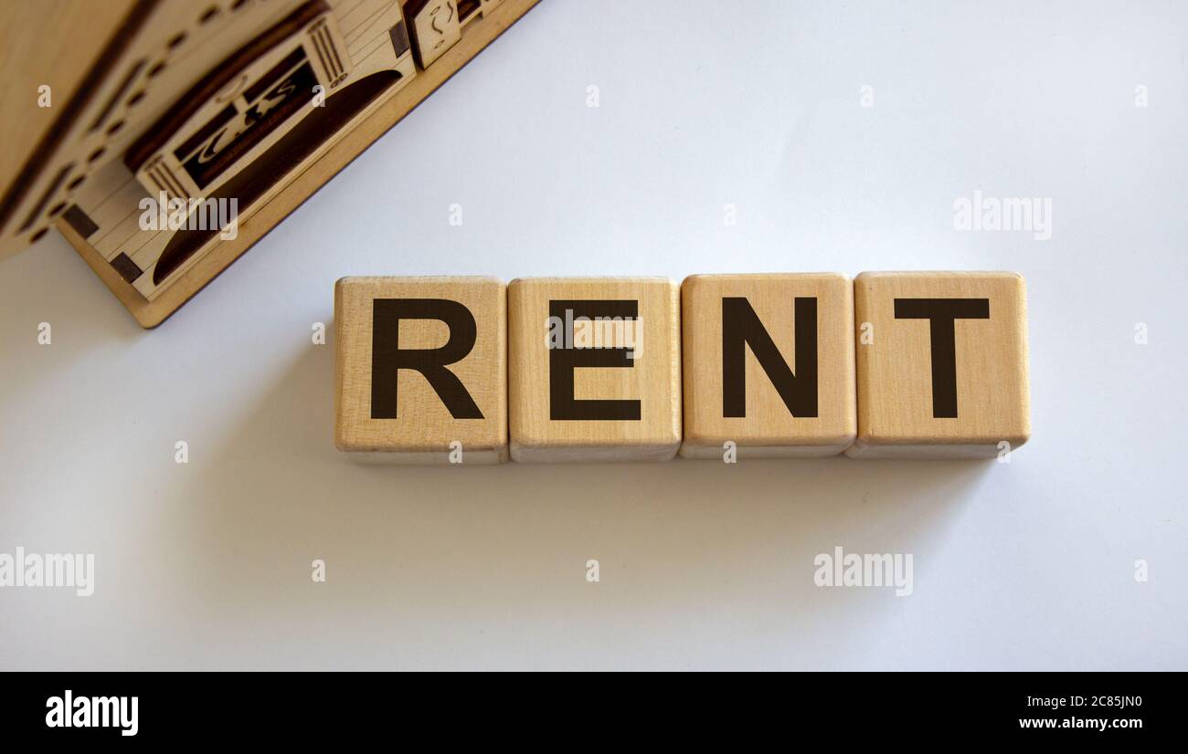 Wooden cubes form the word 'rent' near miniature house. Beautiful white ...