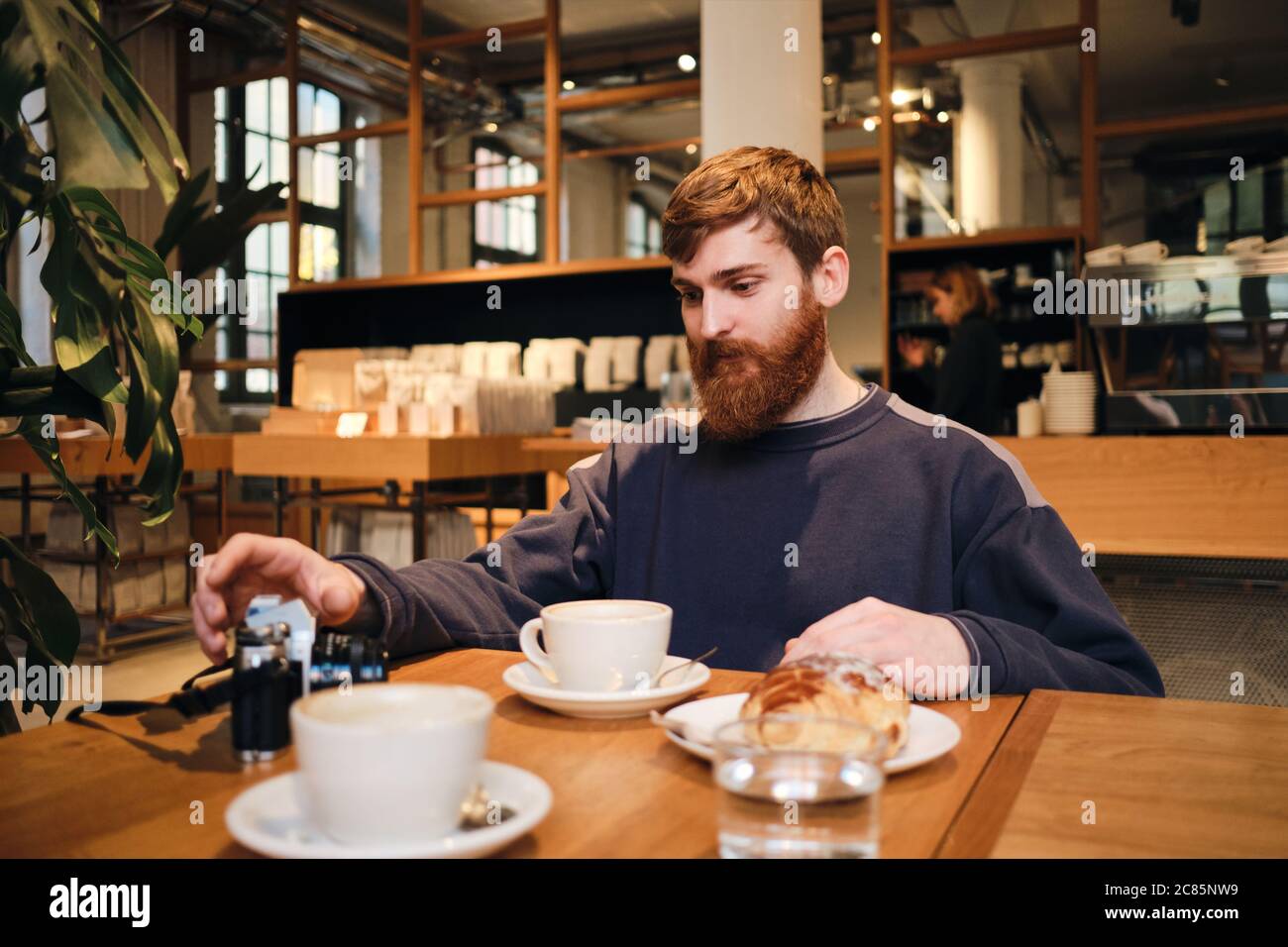 Young handsome bearded man having coffee break in cafe Stock Photo