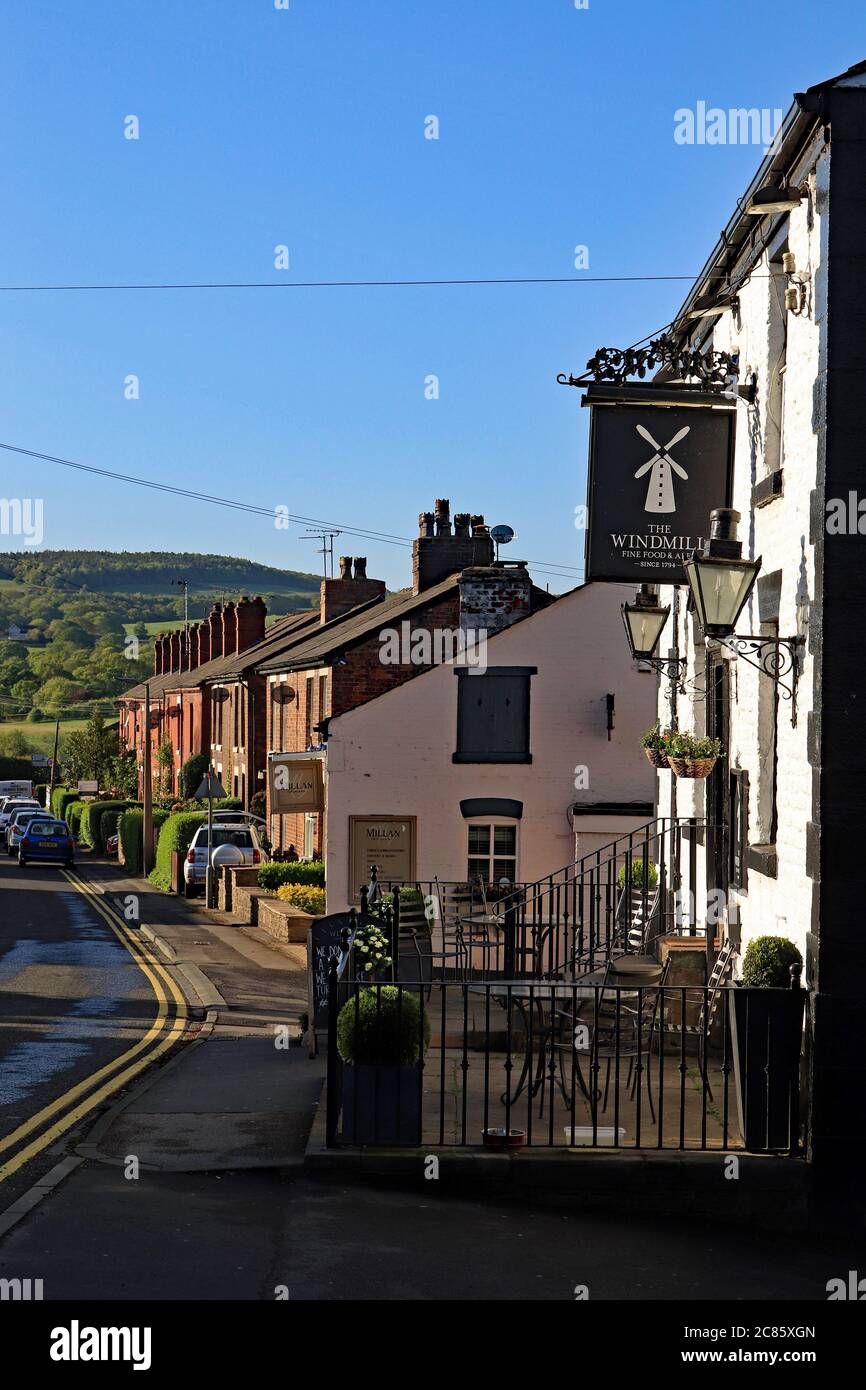 Early morning light illuminates the Wind Mill pub and the cottages along Mill Lane in Parbold. Beyond are the hills of Beacon Fell. Stock Photo