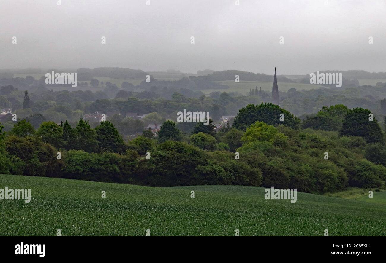 The village of Parbold is seen through the mist of a June morning in 2018.  The village is on the edge West Pennine Hills near the River Douglas. Stock Photo