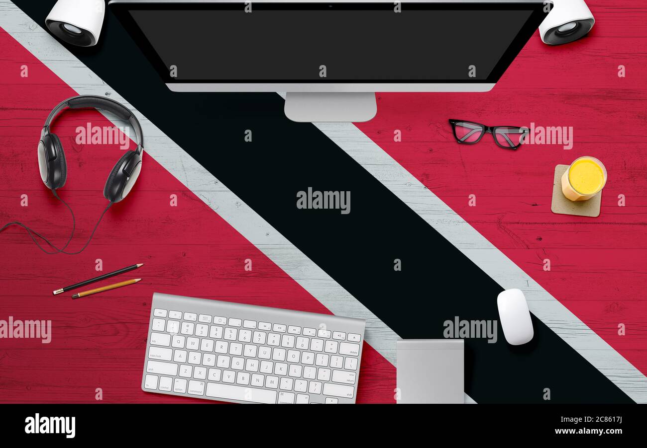 Trinidad And Tobago flag background with headphone,computer keyboard and mouse on national office desk table.Top view with copy space.Flat Lay. Stock Photo