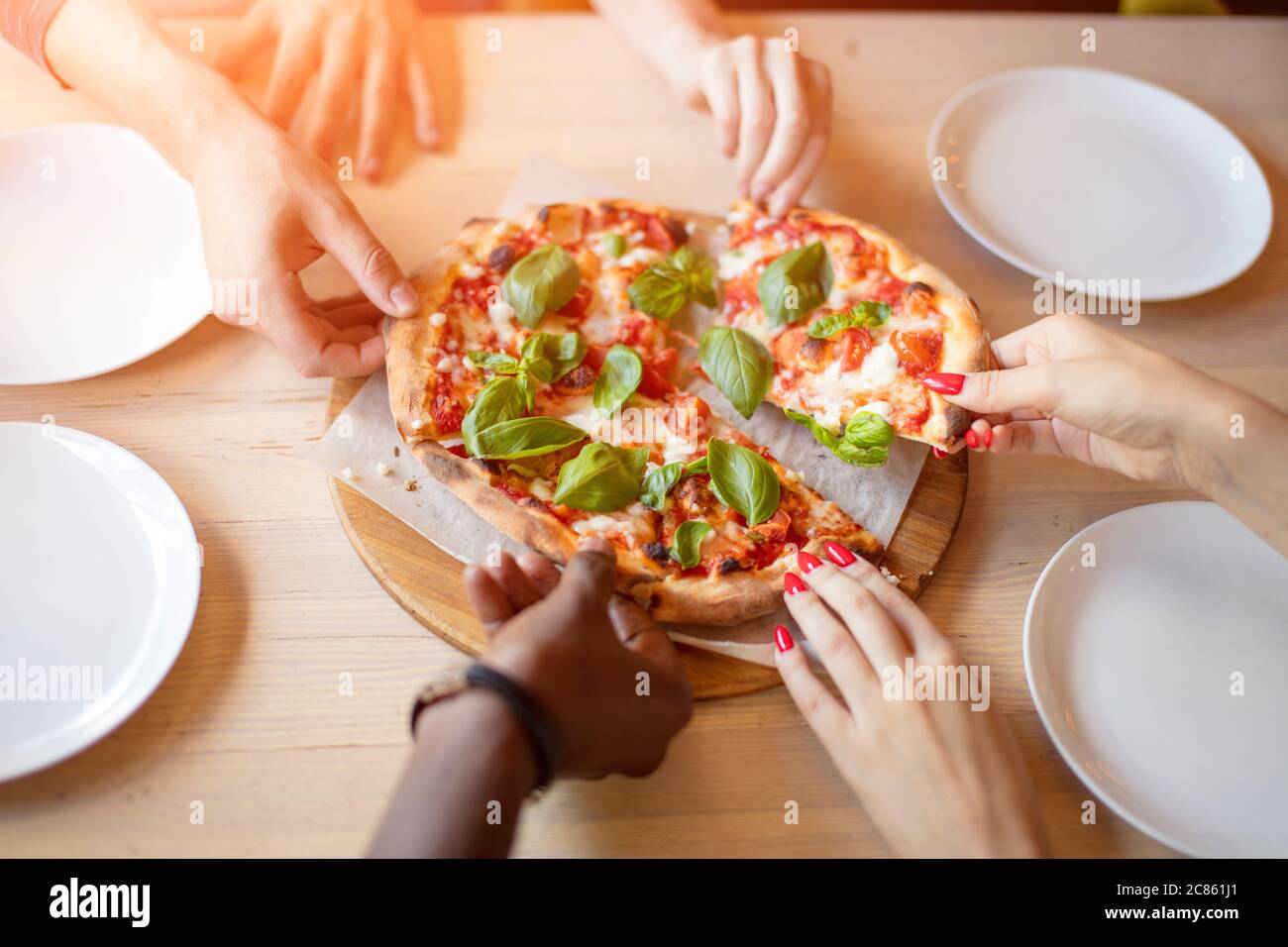 Cheerful Multiracial Friends Eating Delicious Vegetarian Organic Pizza With Basil Leaves At Pizza Hut Close Up Hands Stock Photo Alamy