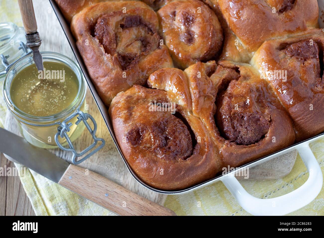 honey yeast cake in baking pan and glass of honey Stock Photo