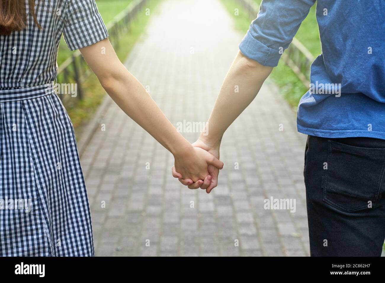 Couple holding hands while walking in the park closeup Stock Photo - Alamy