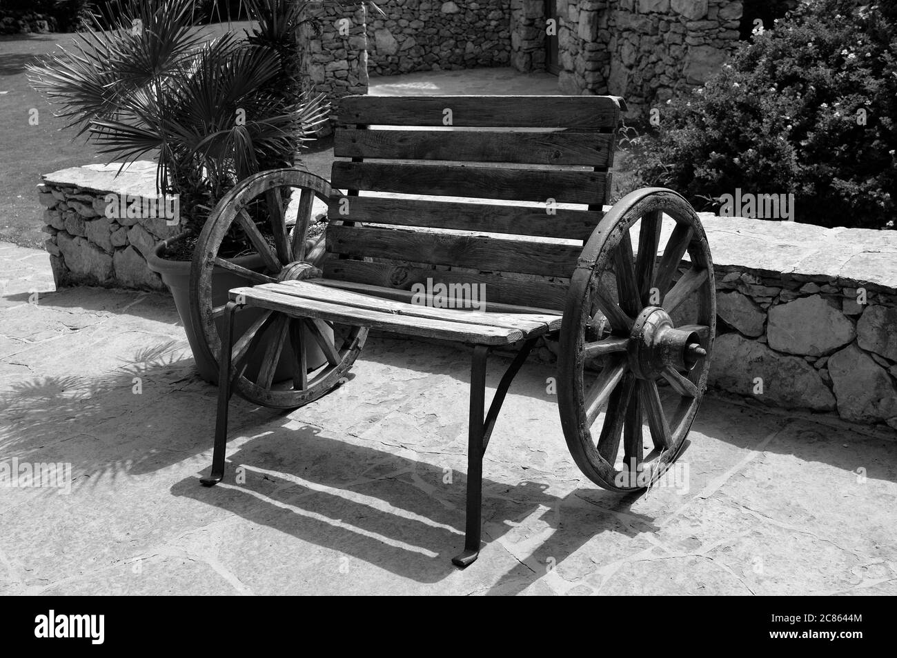 A black & white wooden bench made using two wagon wheels Stock Photo
