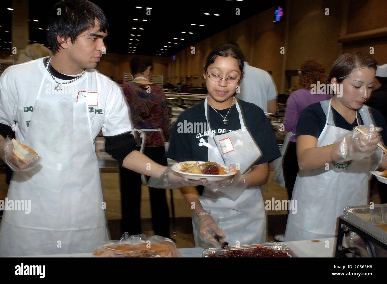 San Antonio, Texas USA, November 24, 2005: Hispanic high school teens put food on plates at the annual Raul Jiminez Thanksgiving Dinner, where more than 25,000 meals on Thanksgiving Day are served for the elderly, homeless, poor and displaced of south Texas. The event, created by the late restauranteur Raul Jiminez, is in its 26th year.   ©Bob Daemmrich Stock Photo