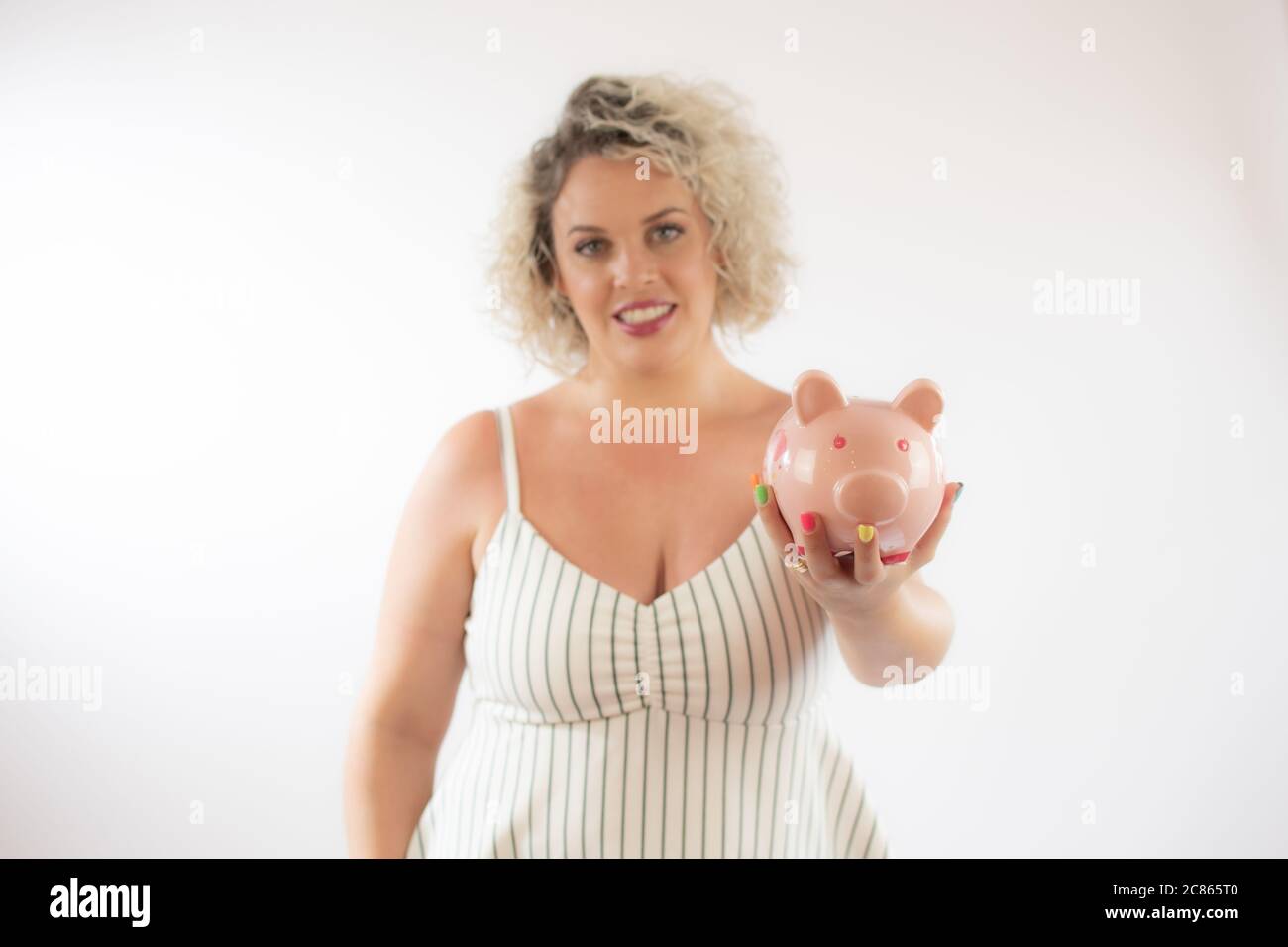 Blonde young woman with a piggy bank Stock Photo - Alamy