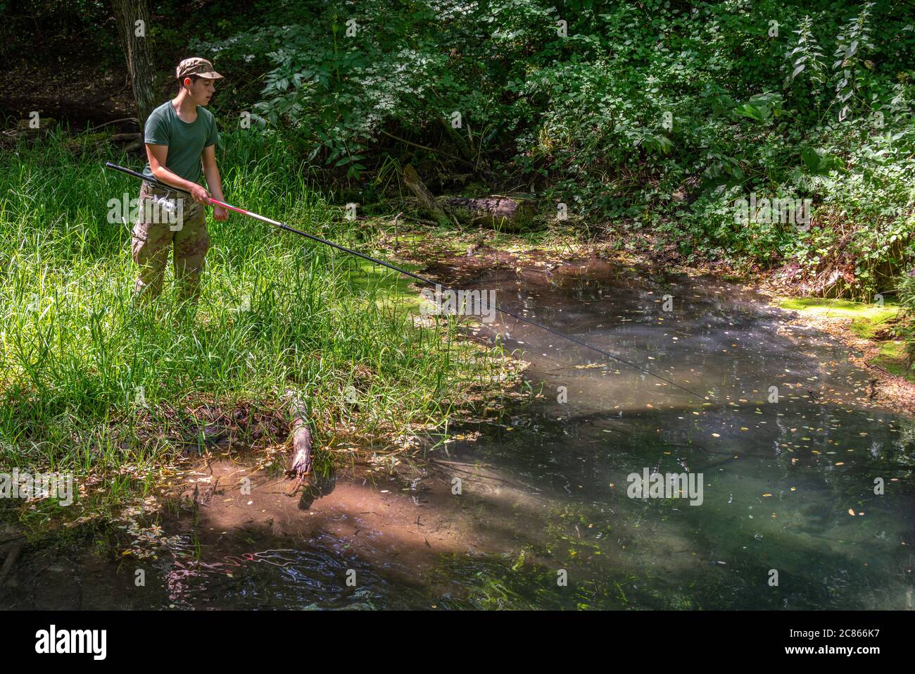 Young beginner boy fishing on the river bank Stock Photo
