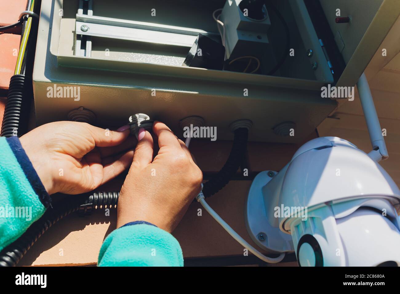 technician female setup cctv camera on wall. Stock Photo