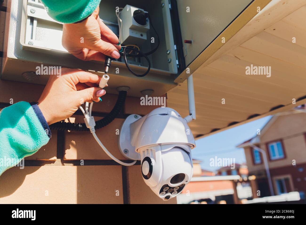 technician female setup cctv camera on wall. Stock Photo