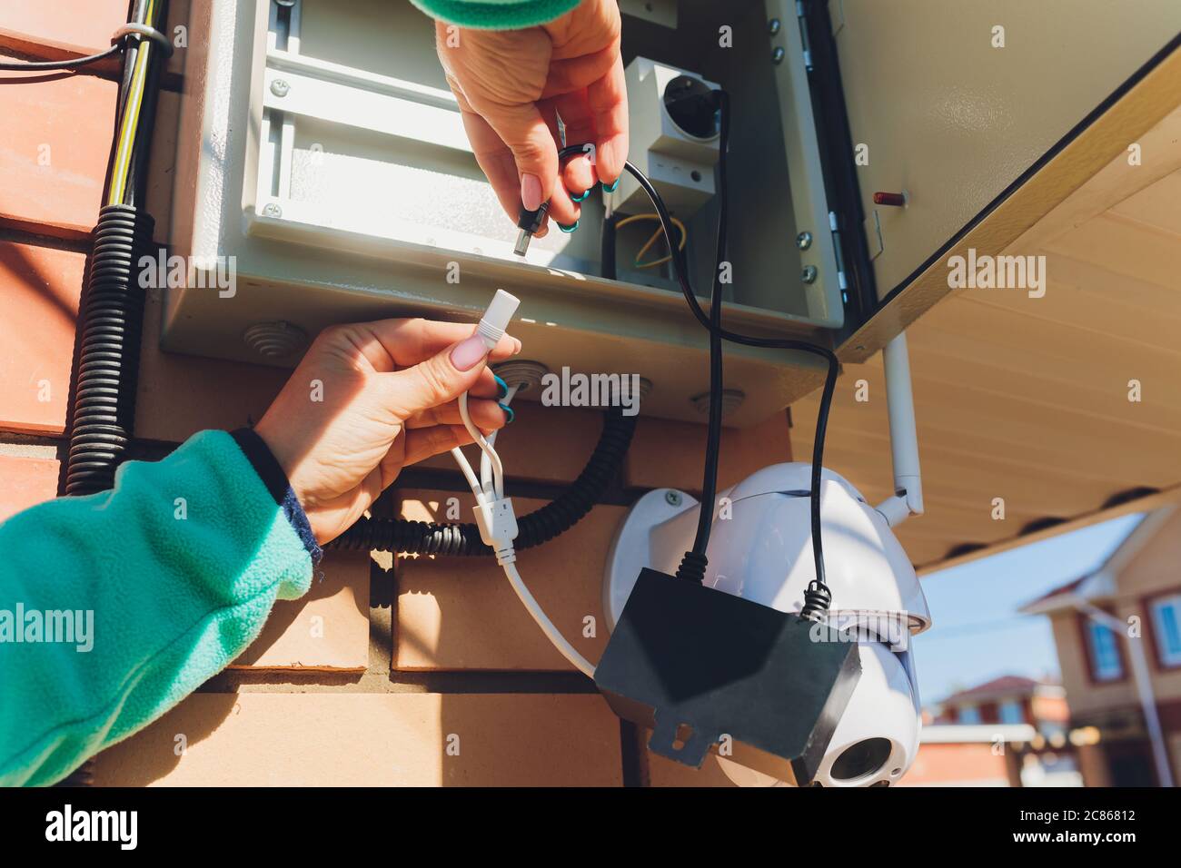 technician female setup cctv camera on wall. Stock Photo