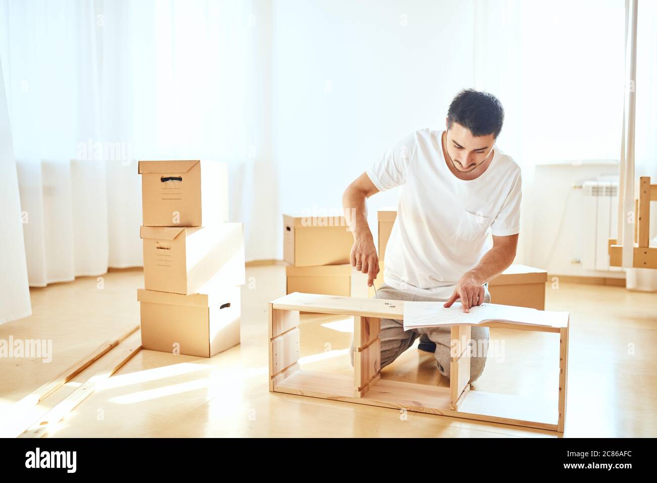 Concentrated Young Man Reading Instructions To Assemble Furniture At Home Stock Photo Alamy