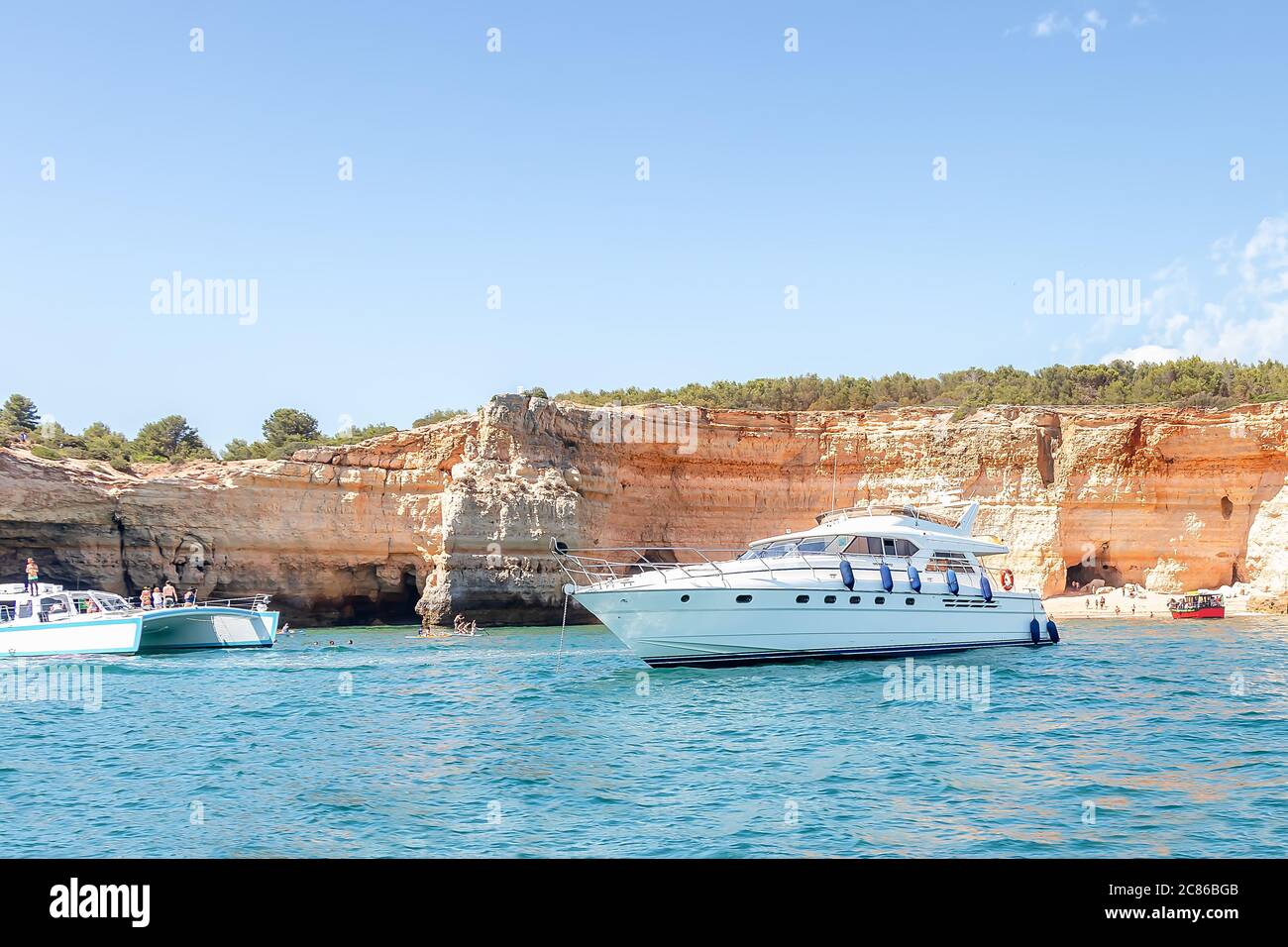 Different kinds of boats in front of Benagil caves and beach with tourists, Algarve, Portugal Stock Photo