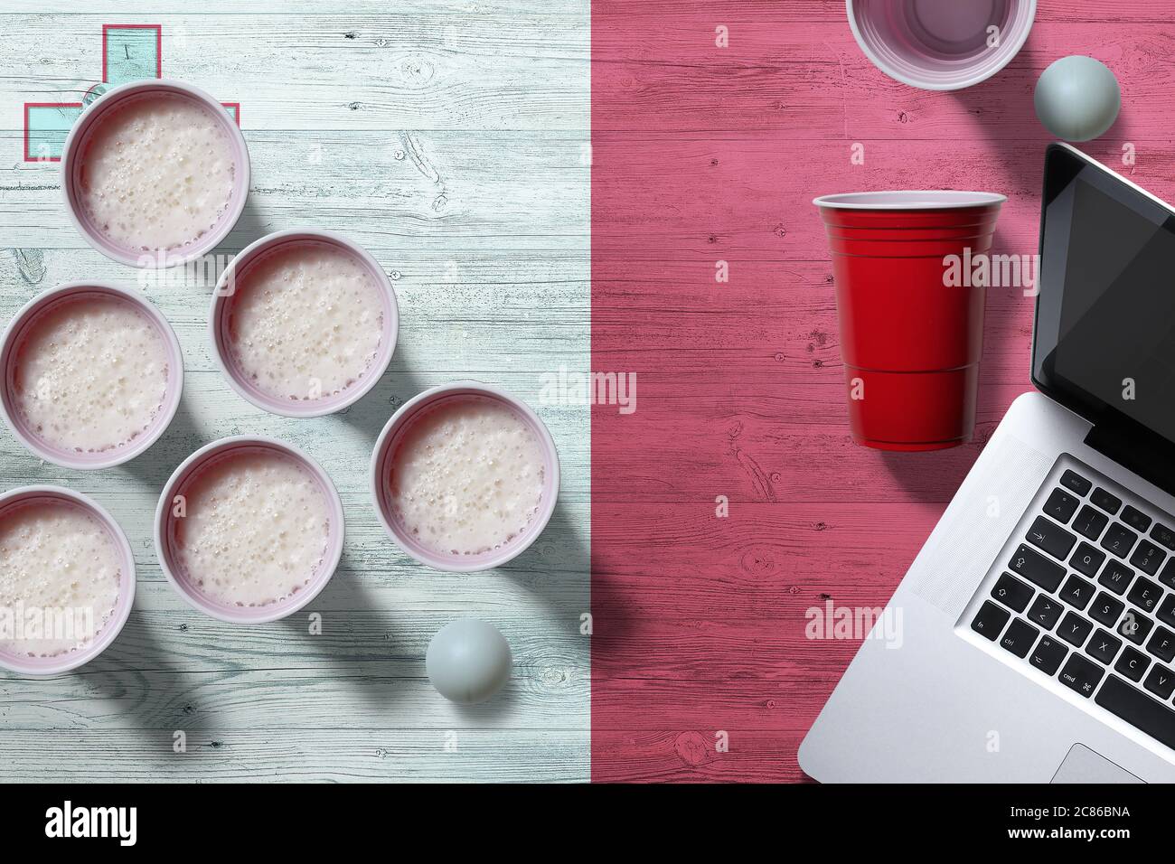 Malta flag concept with plastic beer pong cups and laptop on national wooden table, top view. Beer Pong game. Stock Photo