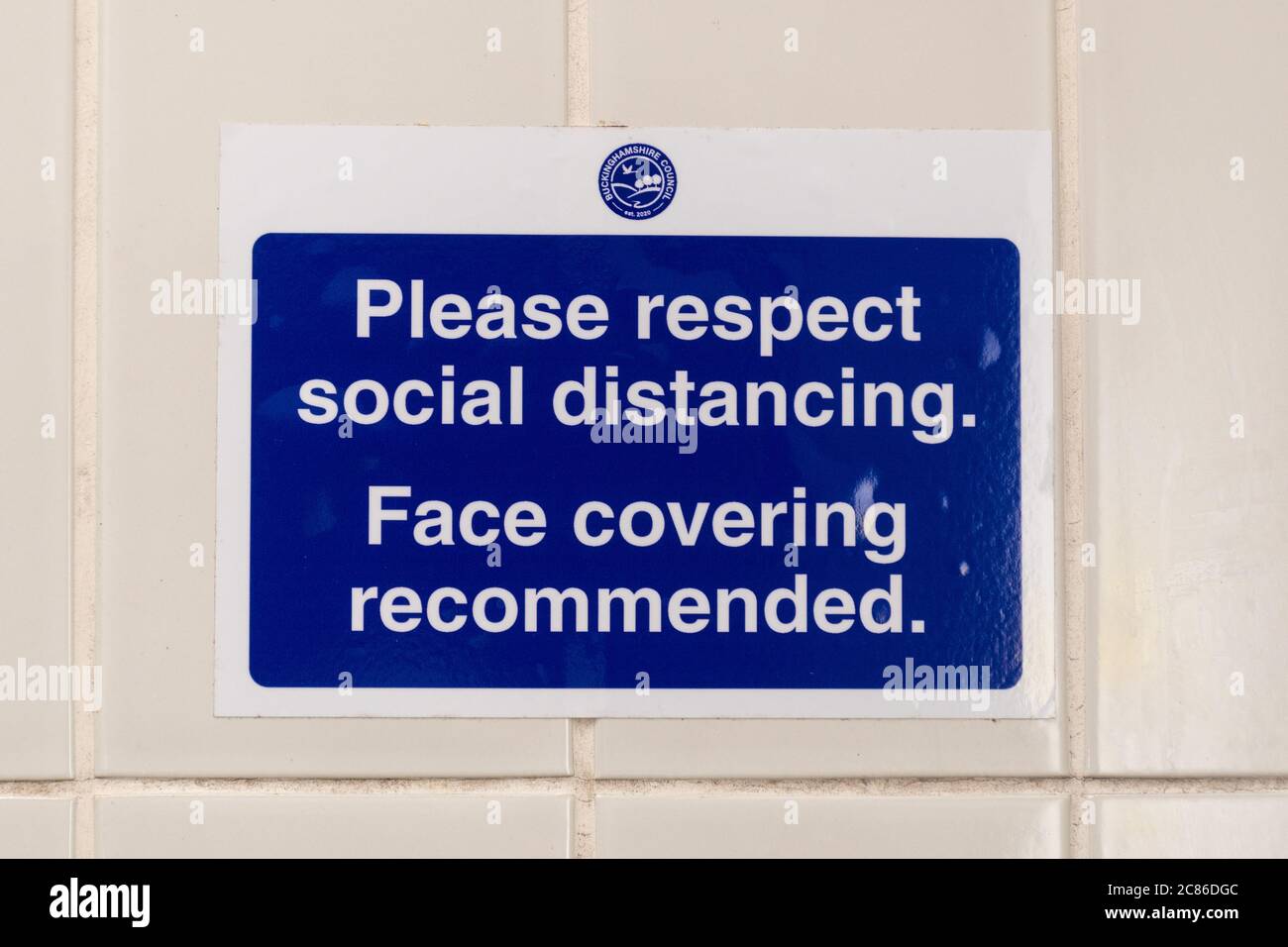 Notice on the wall in a public toilet to Please respect social distancing, face covering recommended, during 2020 coronavirus covid-19 pandemic Stock Photo
