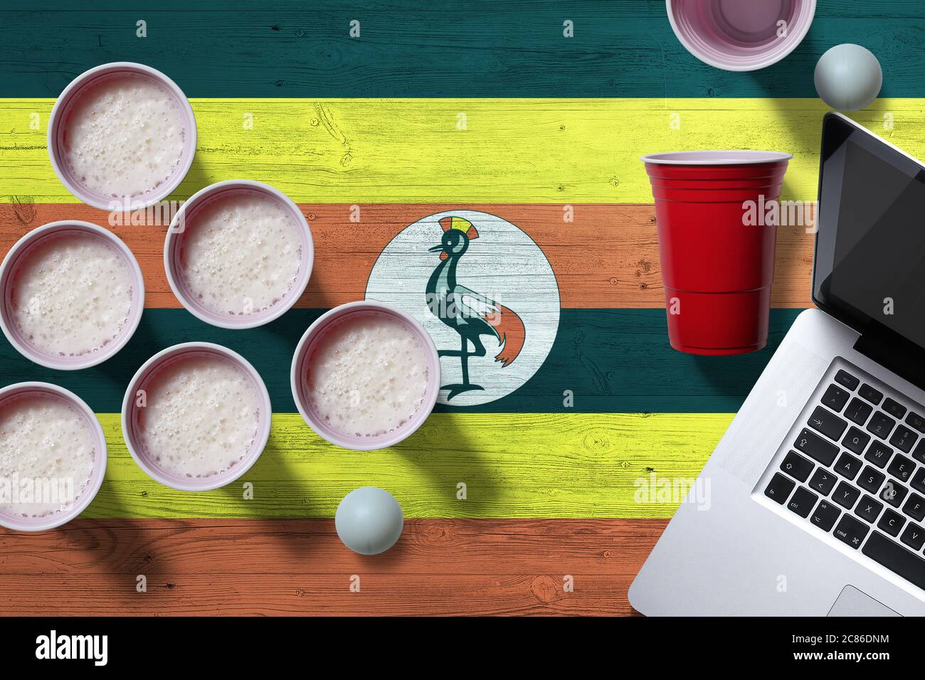 Uganda flag concept with plastic beer pong cups and laptop on national