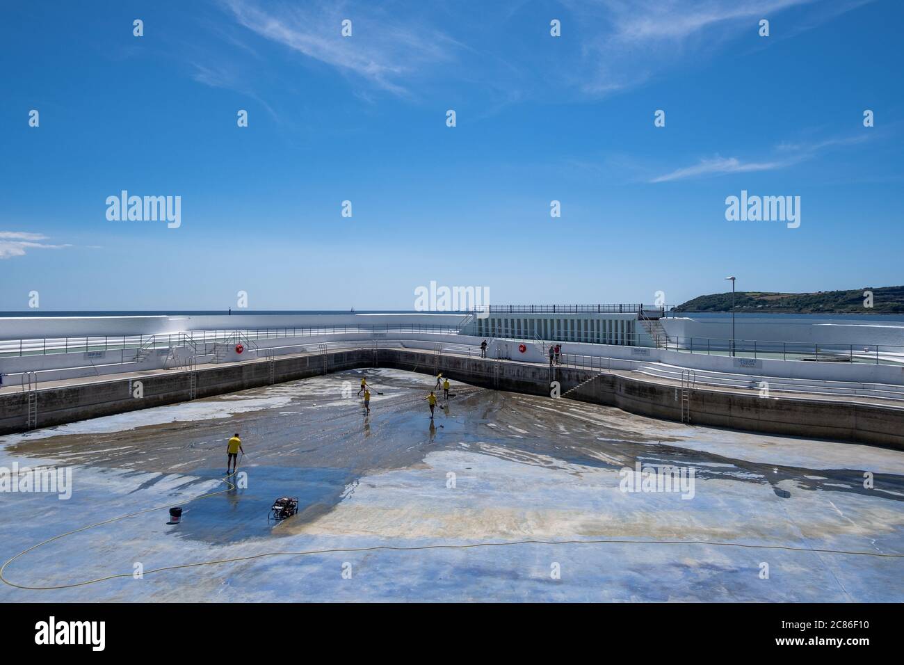 Lifeguards cleaning algae of the bottom of Jubilee Pool, Penzance; pre re-filling and re-opening on 25th July 2020 after the coronavirus lockdown. Stock Photo