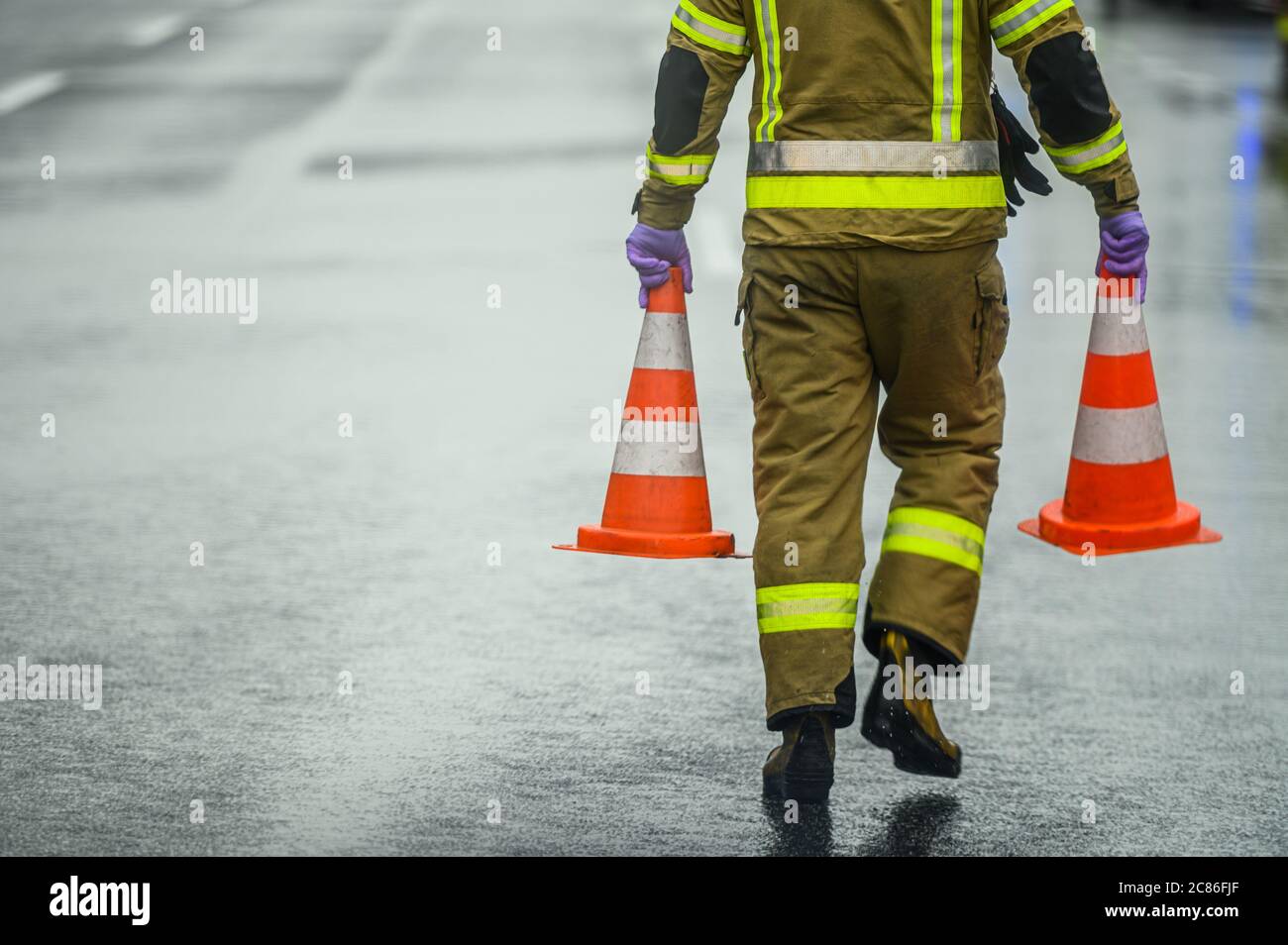 Transportation System Theme. Highway Worker Preparing For Road Closure Moving Two Traffic Cones. Transport Industry. Stock Photo