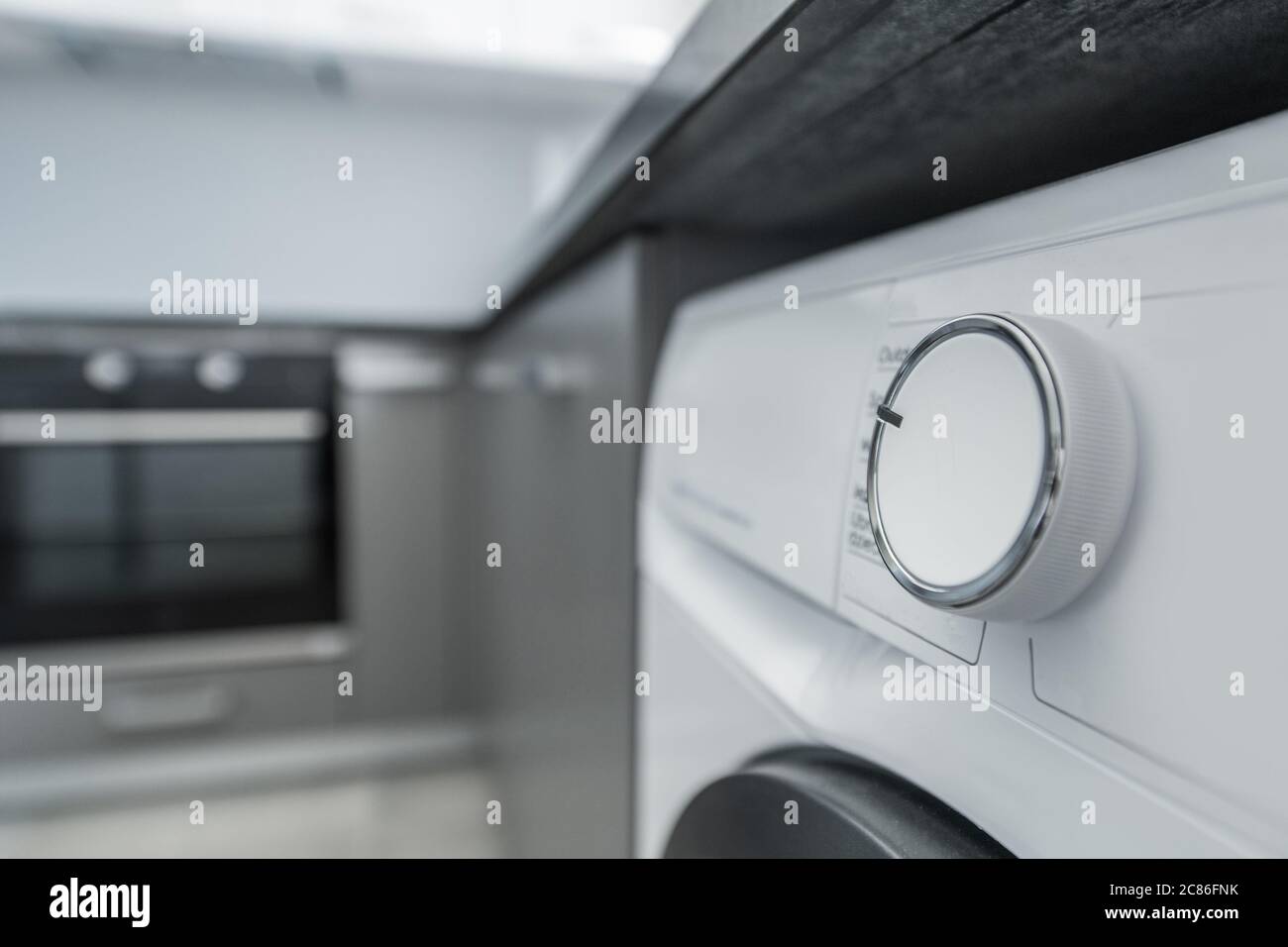 Modern Elegant Washing Machine Inside Apartment Kitchen Space. Home Appliance Used to Wash Laundry.  Programming Dial Button. Stock Photo