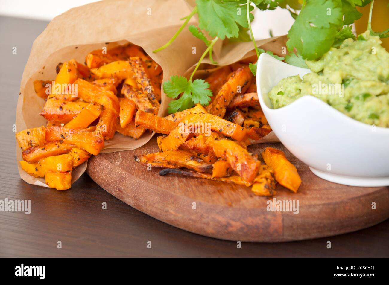 Sweet potato fries with guacamole dip decorated with fresh coriander