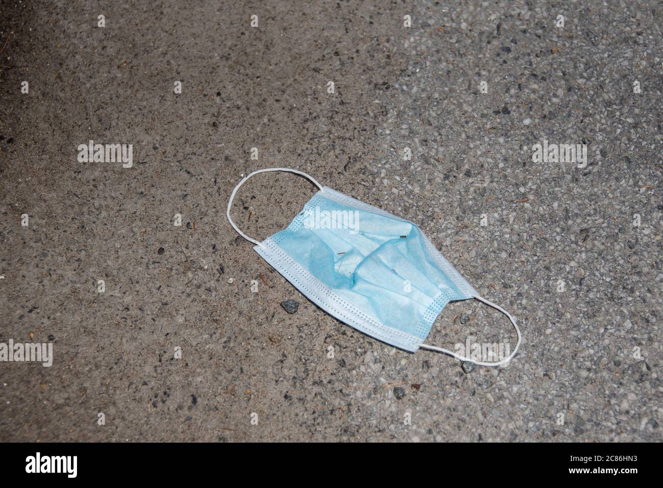 A used disposable face mast discarded in the gutter. Stock Photo