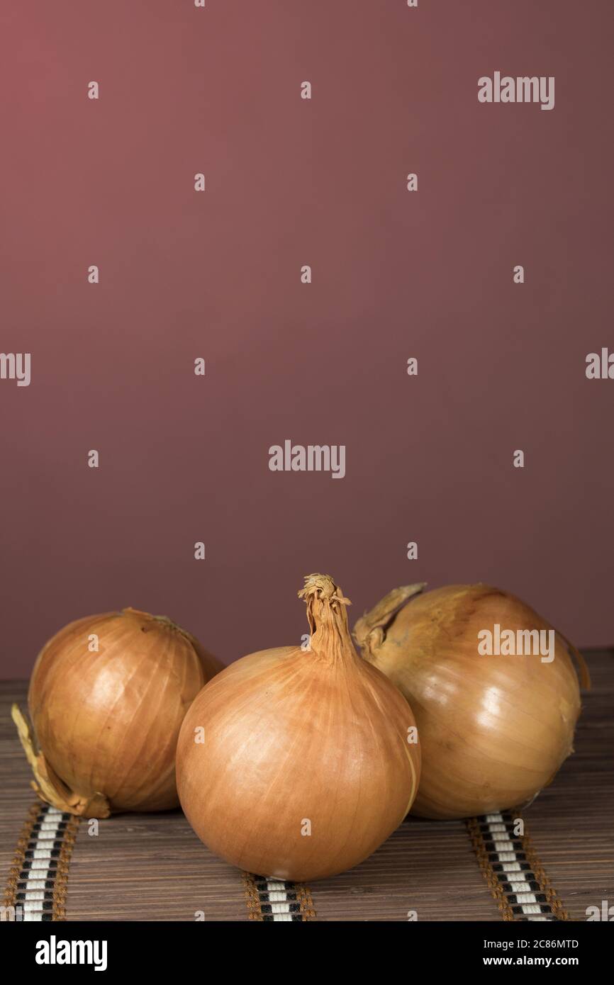 Three onions on board cutting, red background Stock Photo