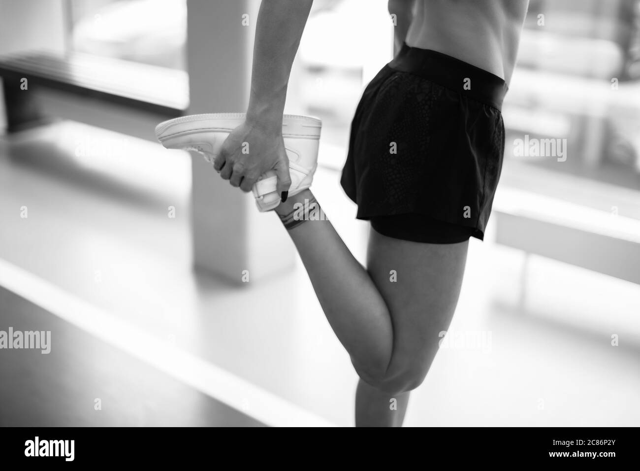 stunning beautiful young fitness woman stretching her legs before workout at gym. preparing exercising flexibility lifestyle sports Stock Photo