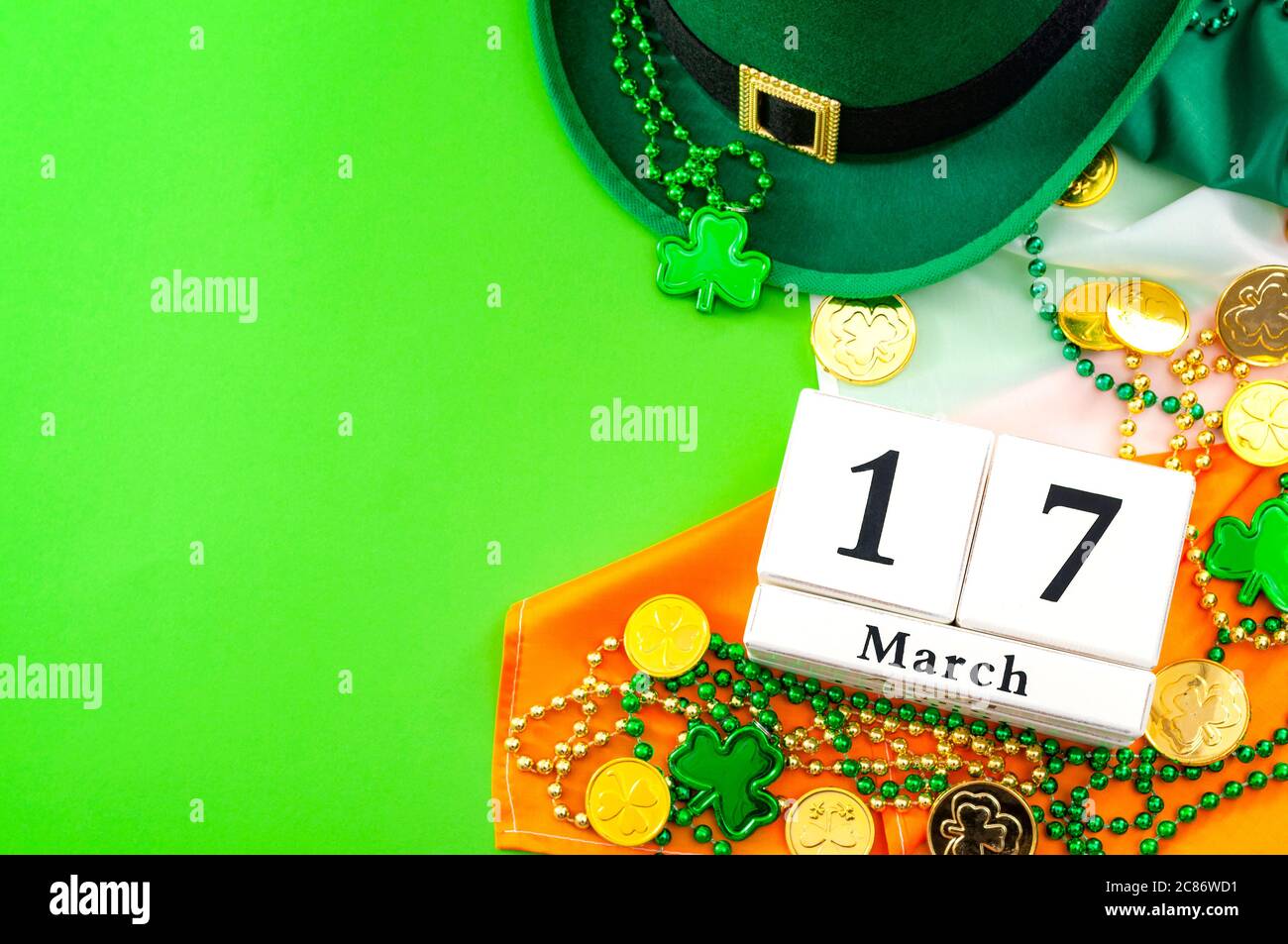 The luck of the Irish meme and Happy St Patricks day concept theme with a calendar, leprechaun hat, beads necklace and gold coins on the Ireland flag Stock Photo