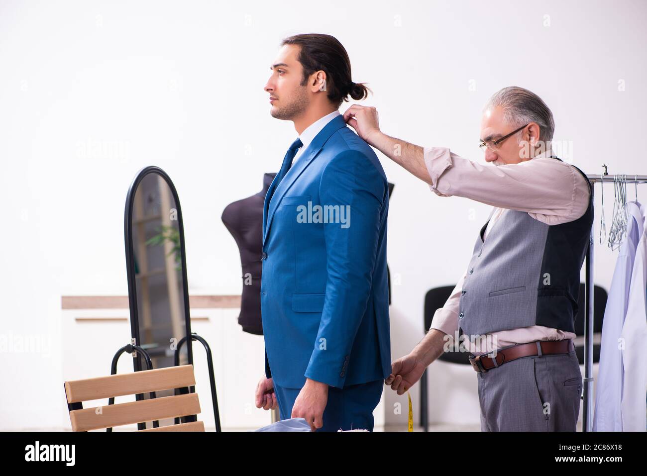 Young businessman visiting old tailor Stock Photo