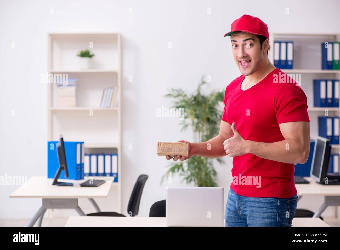 Young courier delivering postbox to the office Stock Photo Alamy