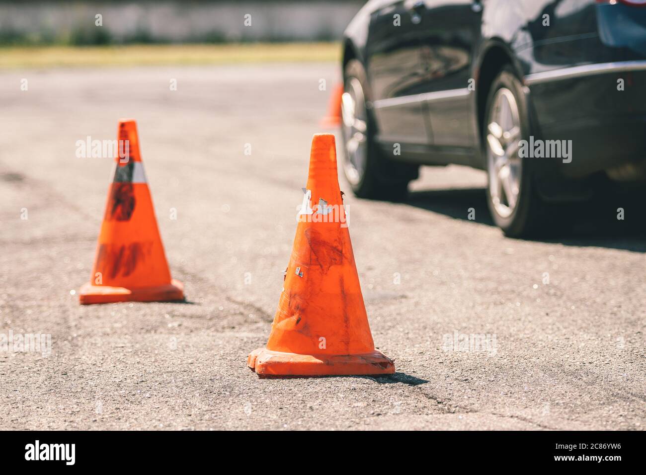 Car and traffic cones, driving school concept. Old orange plastic cone