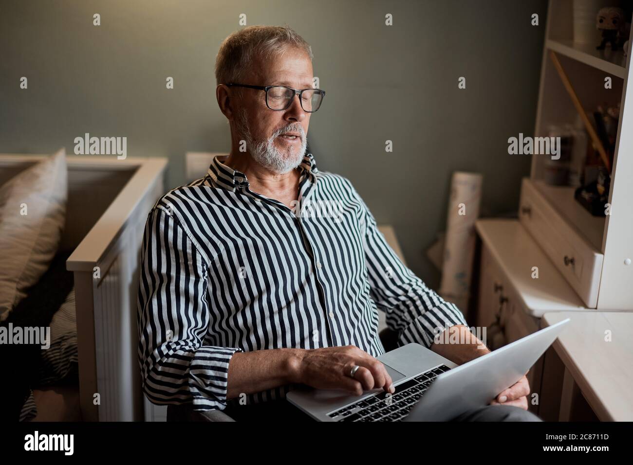 Mature Man Using Laptop On Desk At Home near window Stock Photo - Alamy