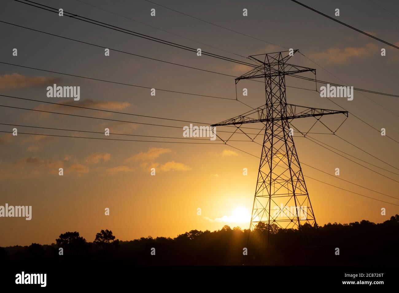 The sun rising behind a towering electricity pylon Stock Photo Alamy