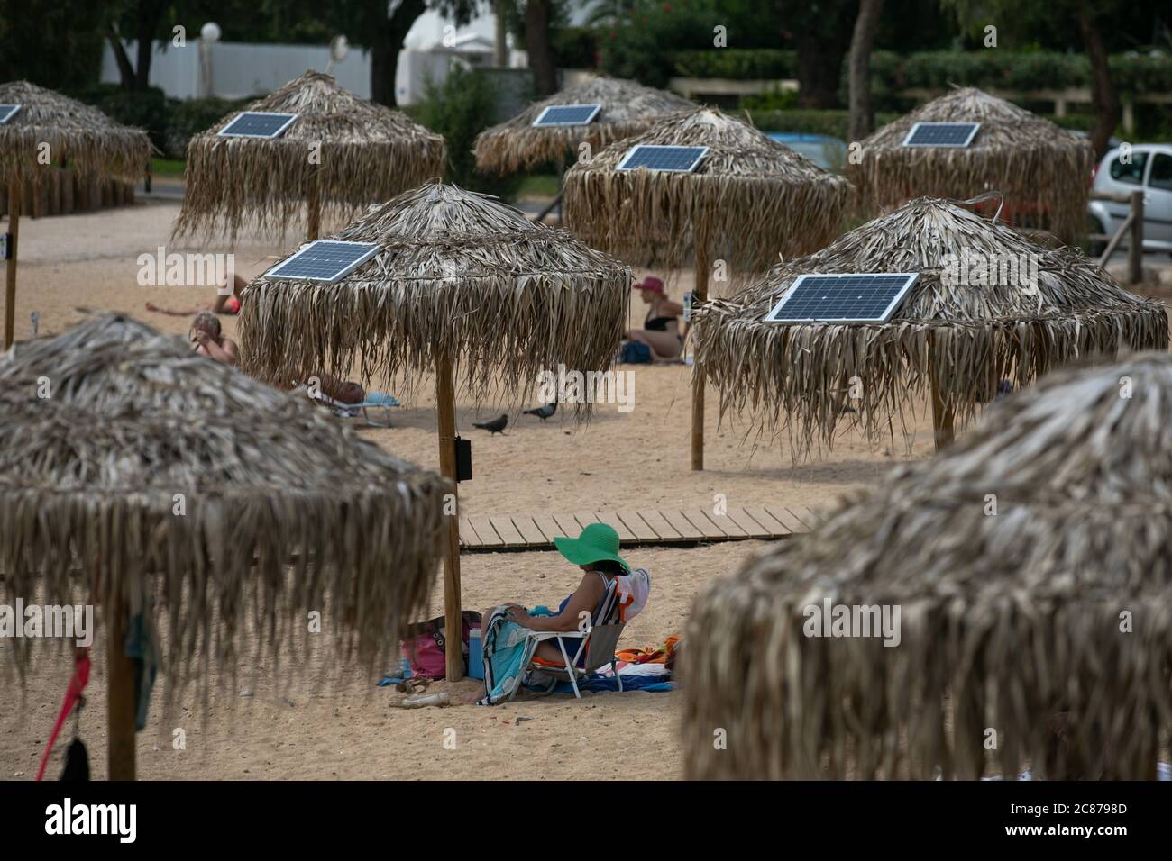 (200721) -- ATHENS, July 21, 2020 (Xinhua) -- Photo taken on July 21, 2020 shows solar panels on umbrellas at an open public beach near the city hall of Vari-Voula-Vouliagmeni municipality in southern Athens, Greece. As of Tuesday, the dozens of umbrellas scattered along the beach, in line with the safe distancing measures for protection against COVID-19, are fitted with a system consisting of solar panels and USB ports offering free of charge and environmentally friendly charging. Under a pilot program launched on Tuesday, sunbathers will be contributing to energy-saving efforts using solar e Stock Photo