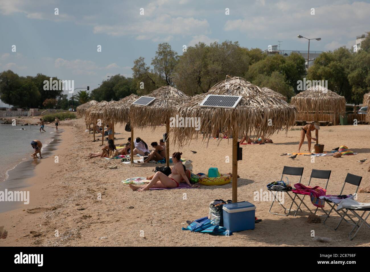 (200721) -- ATHENS, July 21, 2020 (Xinhua) -- Photo taken on July 21, 2020 shows solar panels on umbrellas at an open public beach near the city hall of Vari-Voula-Vouliagmeni municipality in southern Athens, Greece. As of Tuesday, the dozens of umbrellas scattered along the beach, in line with the safe distancing measures for protection against COVID-19, are fitted with a system consisting of solar panels and USB ports offering free of charge and environmentally friendly charging. Under a pilot program launched on Tuesday, sunbathers will be contributing to energy-saving efforts using solar e Stock Photo