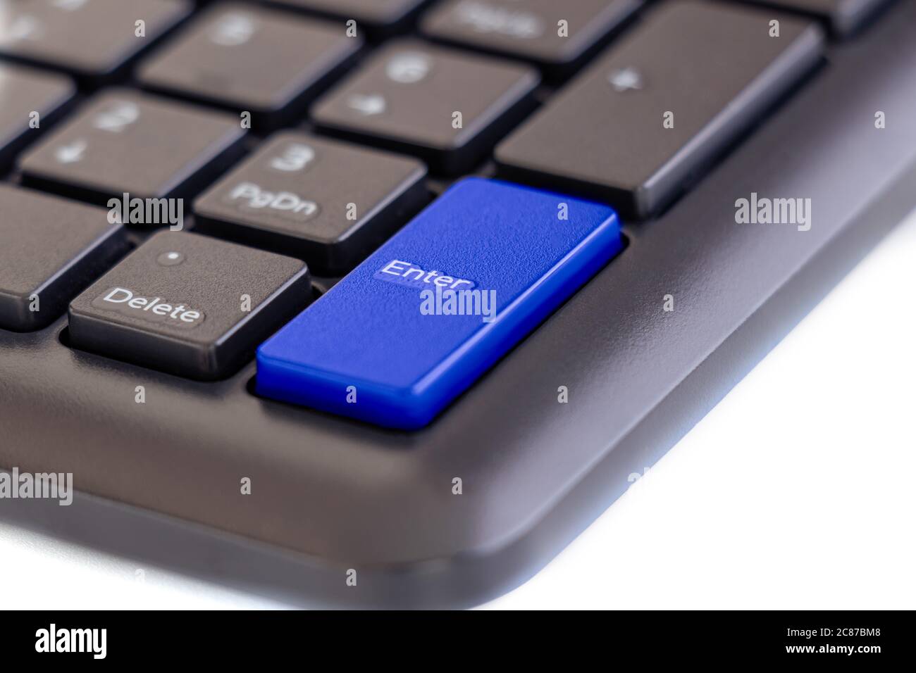 Enter key highlight with blue color on keyboard with finger pressing button on white background, selective focus Stock Photo