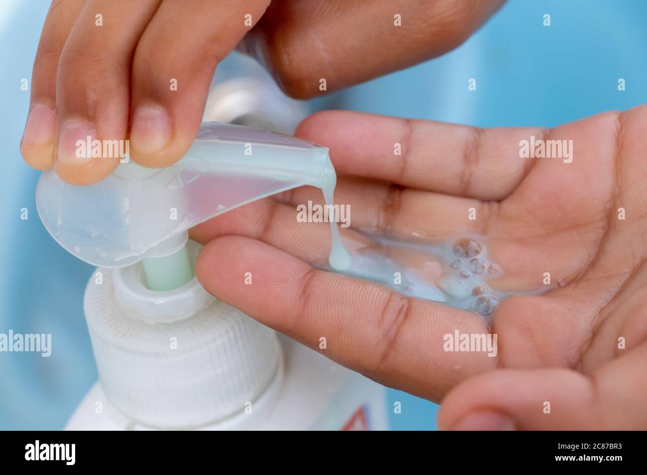Hand takes liquid soap from a soap dispenser to wash hands at the sink Stock Photo